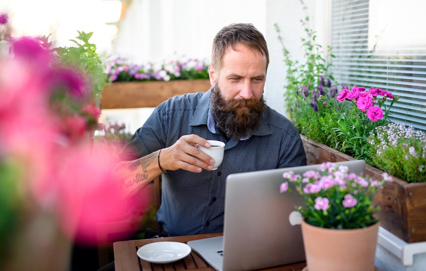 Homeoffice im Gartenhaus – die ideale Work-Life-Balance Mann arbeitet entspannt mit Kaffee am Laptop auf seiner Terrasse